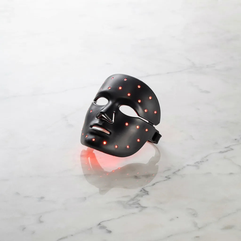 LumaGlow LED Light Therapy Mask — black silicone mask with red LED lights on white marble surface